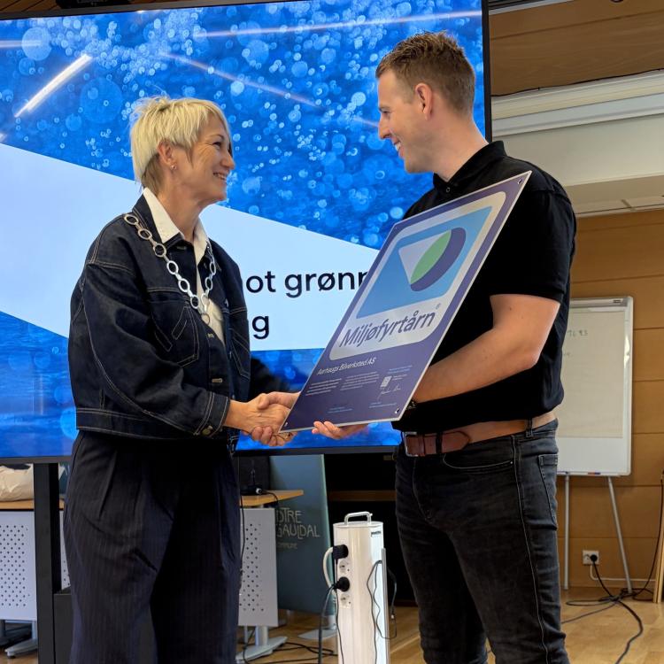 Bilde av ordfører Trude Heggdal som deler ut plaketten fra Miljøfyrtårn til Andreas Aarhaug fra Aarhaug bilverksted. 