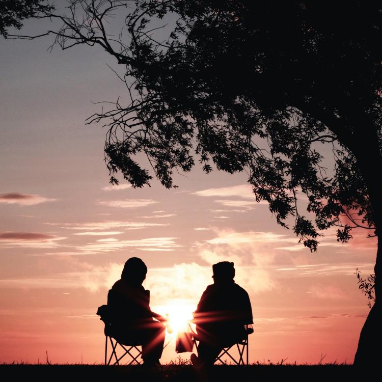 illustrasjon - to personer som sitter sammen i solnedgangen